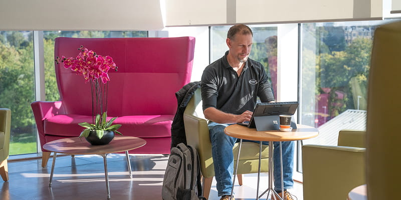 Man sitting on chair and browses a tablet inside the Beatson Wellbeing Centre